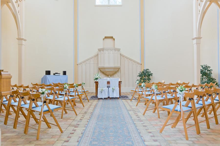 bestuhlter, geschmückter Kircheninnenraum mit Backsteinfußboden