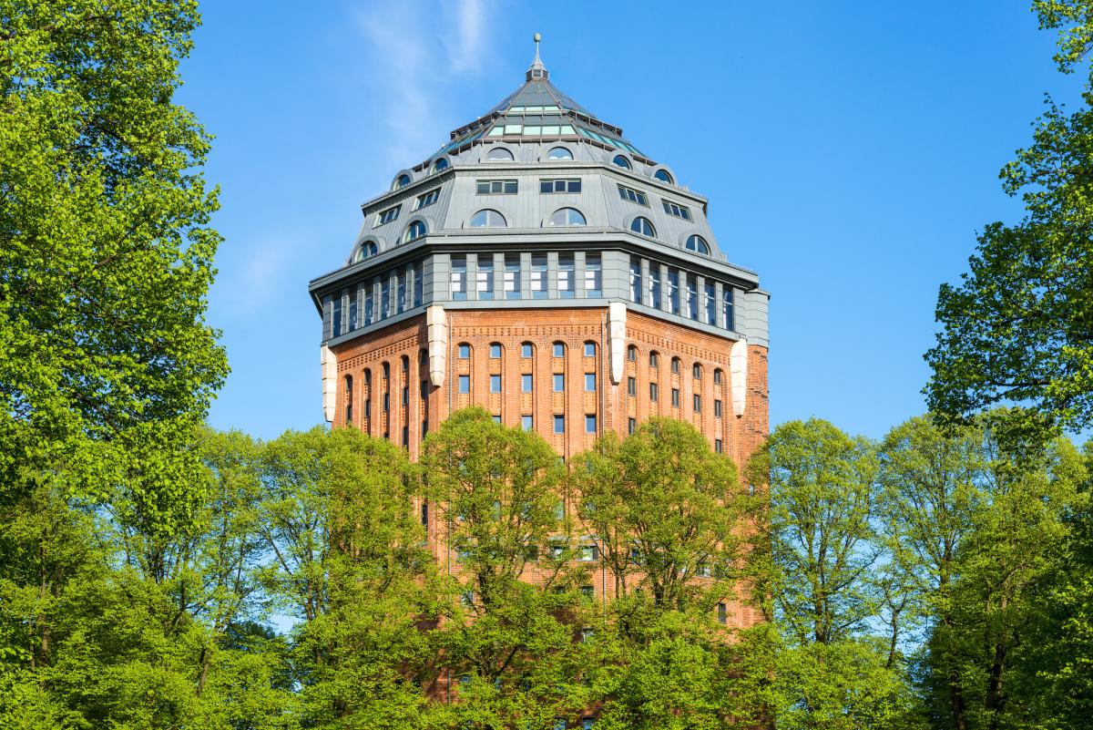 Wasserturm aus rotem Backstein mit achteckigem Spitzdach im Park