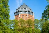 Wasserturm aus rotem Backstein mit achteckigem Spitzdach im Park